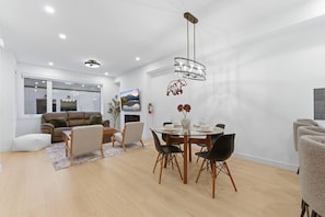 A modern living room with a dining area, a sofa, a coffee table, and a chandelier. - Spacious Calgary Home | Rooftop Views | Sleeps 10 (Calgary)