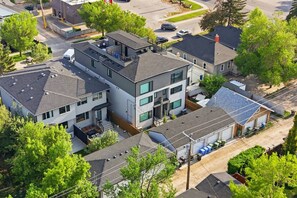 A modern multi-story residential building with a rooftop deck, large windows, and a garage. - Spacious Calgary Home | Rooftop Views | Sleeps 10 (Calgary)