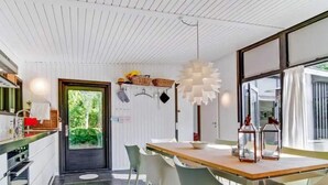 Una cucina moderna con un piano di lavoro in legno, mobili bianchi e una porta nera.