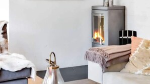 Un accogliente soggiorno con camino, un divano, un tavolino da caffè con una lanterna e una mensola a muro.