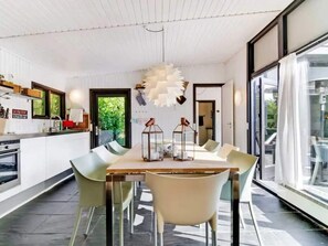 A modern kitchen with a dining area, large windows, and a view of greenery outside. - 4 Star Holiday Home in Dronningmolle (Dronningmolle)