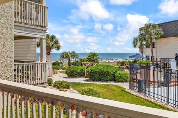 A beachfront property with a balcony, palm trees, and a view of the ocean. - Ocean Forest Villas B112 (Myrtle Beach)