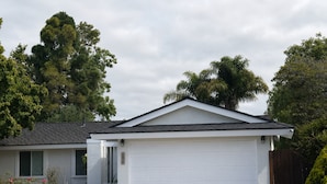 A single-story house with a garage, a driveway, and a small garden with red flowers. -  4BR Near UCSB & Santa Barbara • Private Hot Tub • Walk to Beach • Pool access (Goleta)