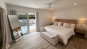 A bedroom with a bed, bedside tables, a ceiling fan, and a sliding glass door leading to an outdoor seating area. -  4BR Near UCSB & Santa Barbara • Private Hot Tub • Walk to Beach • Pool access (Goleta)