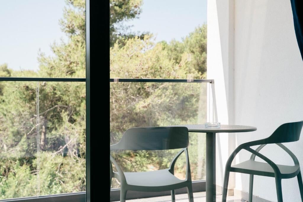 A balcony with two chairs and a table, overlooking a forested area.