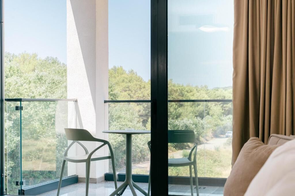 Un balcón con puerta de cristal, dos sillas y una mesa.