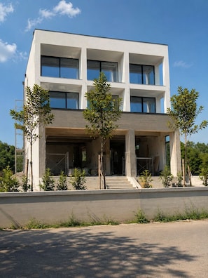 Ein modernes Gebäude mit flachem Dach, großen Fenstern und einem überdachten Eingangsbereich.
