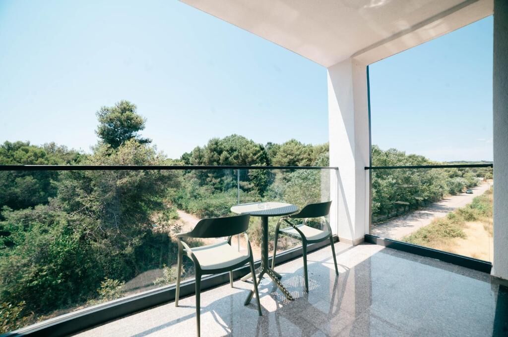 A balcony with a table and chairs, overlooking a natural landscape.