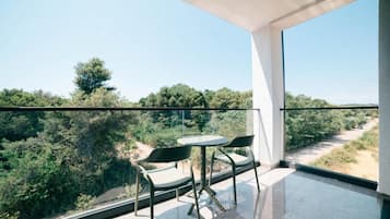 A balcony with a table and chairs, overlooking a natural landscape.