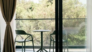 Un balcón con dos sillas y una mesa, con vista a una zona boscosa.
