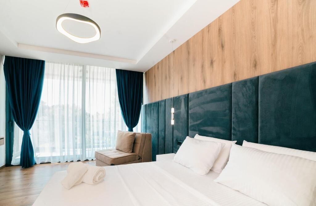 Habitación de hotel con una cama grande, zona de estar y vistas por la ventana.