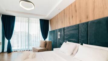Habitación de hotel con una cama grande, zona de estar y vistas por la ventana.