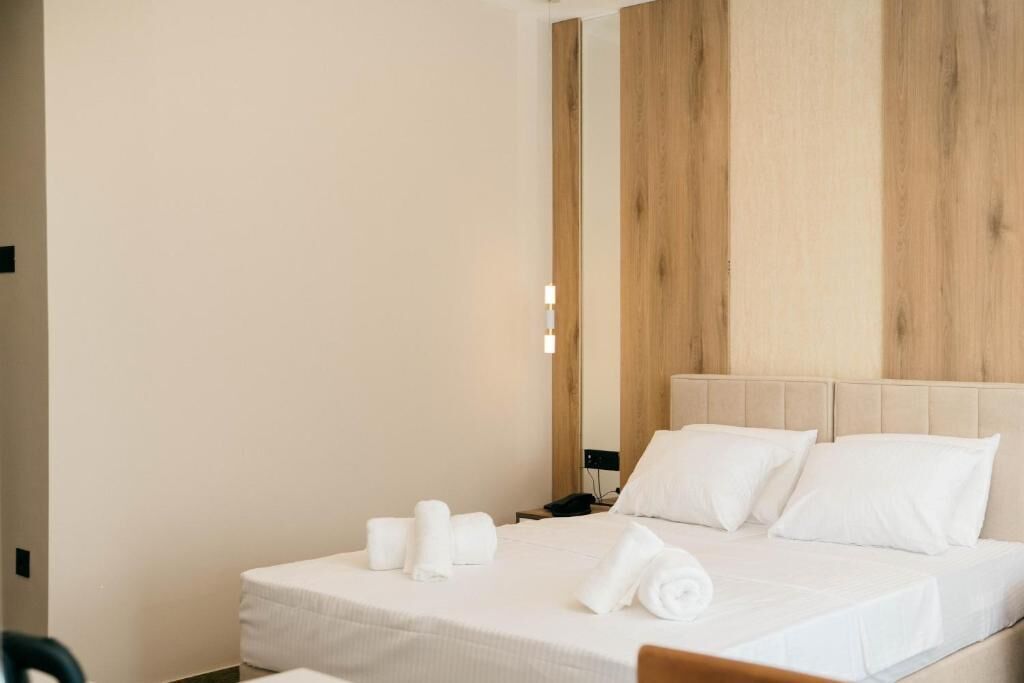 Et hotelværelse med en seng, et natbord og en vægmonteret lampe.