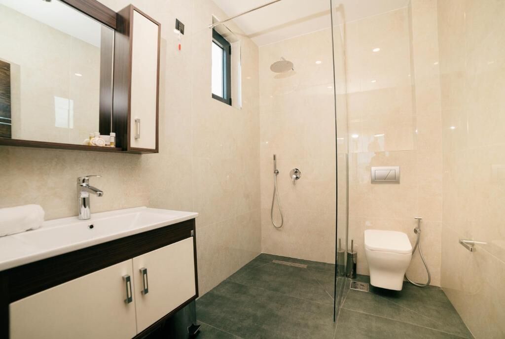 A modern bathroom with a glass-enclosed shower, a white sink, and a toilet.