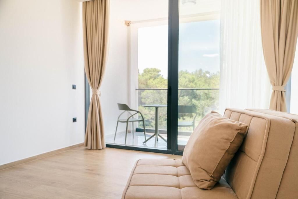 Uma sala de estar moderna com um sofá, uma janela grande e vista para o exterior.