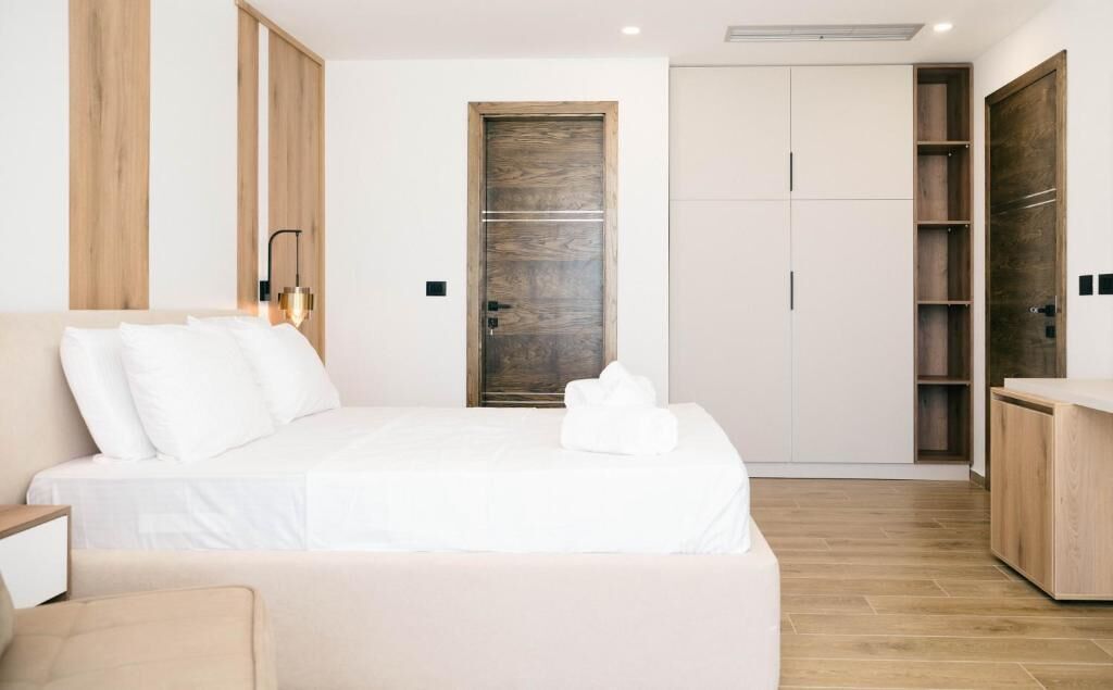 A modern bedroom with a large bed, a wooden wardrobe, and a built-in bench.