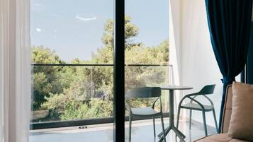 A balcony with a view of trees, a sofa, and two chairs.