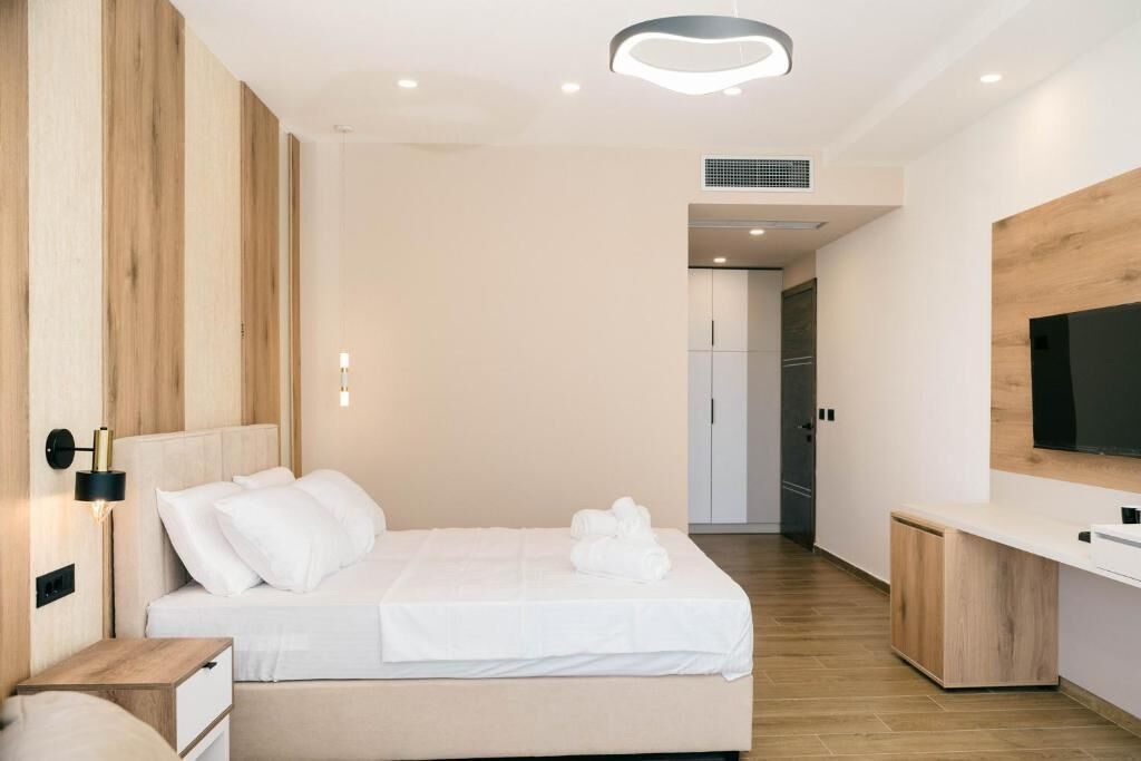 A modern hotel room with a bed, bedside table, and a TV mounted on the wall.