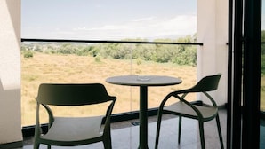 Un balcón con una mesa y dos sillas, con vistas a un paisaje cubierto de hierba.