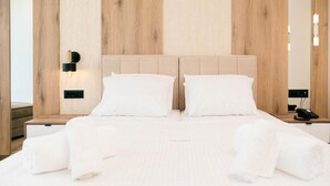 Habitación de hotel con una cama grande, paredes de paneles de madera, una mesita de noche con teléfono e iluminación montada en la pared.