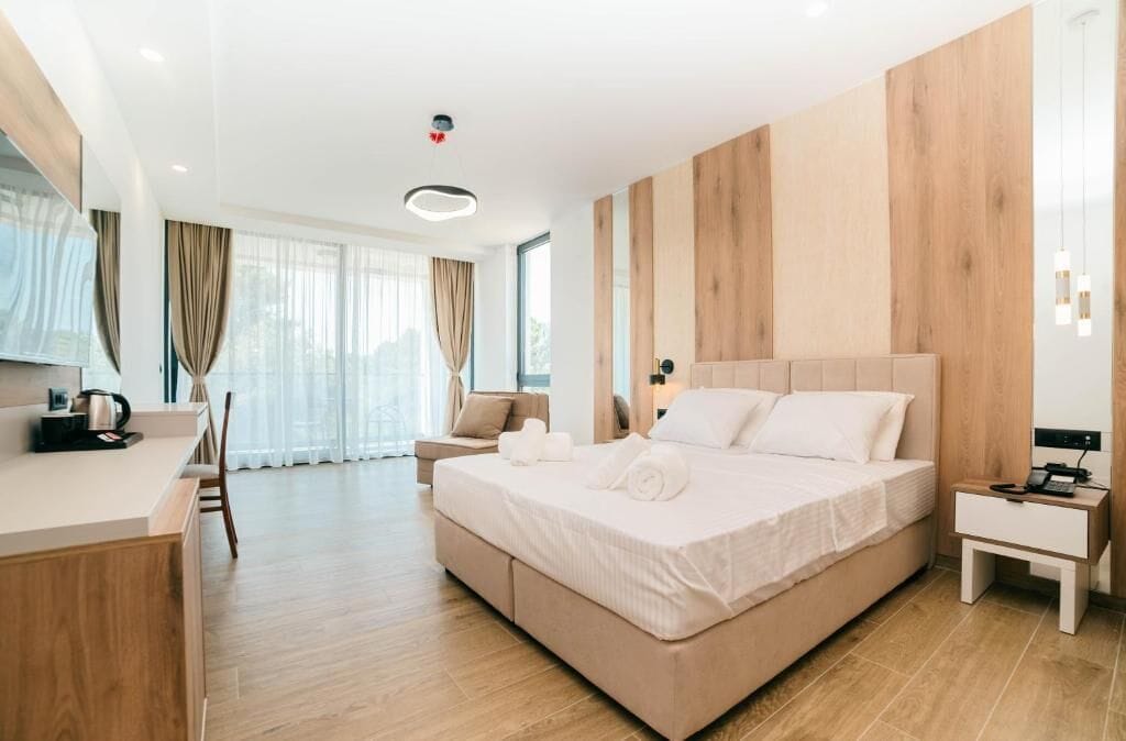 A modern hotel room with a large bed, a desk, and a chair.