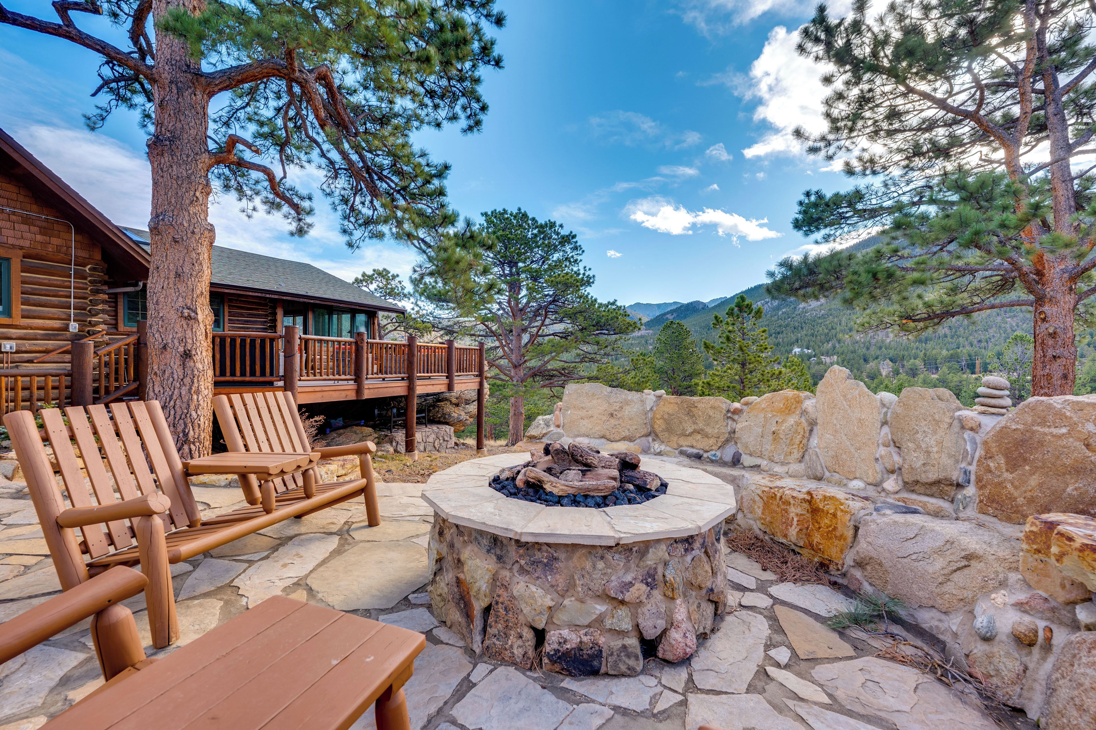 A wooden deck with lounge chairs and a stone fire pit.