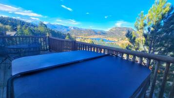 A pool table on a deck with a view of mountains and a lake.