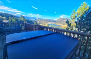 Mesa de bilhar em um deck com vista para montanhas e um lago.