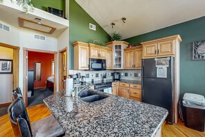 A kitchen with granite countertops, wooden cabinets, a refrigerator, and a microwave. - Two BR Condo w/ Brand NEW HOT TUB and Great Views! (Estes Park)