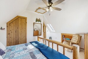 A bedroom with a bed, wooden headboard, a ceiling fan, a wooden wardrobe, a mirror, a bookshelf, and a skylight. - Spacious Cabin With Stunning Views, Wifi, Fully Stocked Kitchen & W/D (Drake)