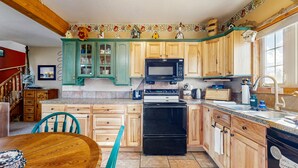 A kitchen with wooden cabinets, a black microwave, a stove, and a sink. - Spacious Cabin With Stunning Views, Wifi, Fully Stocked Kitchen & W/D (Drake)