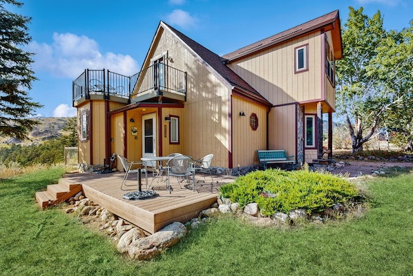 A two-story house with a deck, outdoor seating, and a small garden.