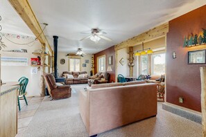 Ein gemütliches Wohnzimmer mit Kamin, Holzbalken und einer Essecke mit Tisch und Stühlen.