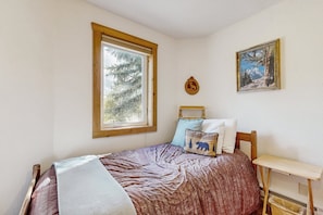 A bedroom with a bed, a window, a small table, and two wall-mounted pictures. - Spacious Cabin With Stunning Views, Wifi, Fully Stocked Kitchen & W/D (Drake)