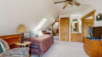 A bedroom with a bed, a desk, a chair, a dresser, a mirror, and a ceiling fan.