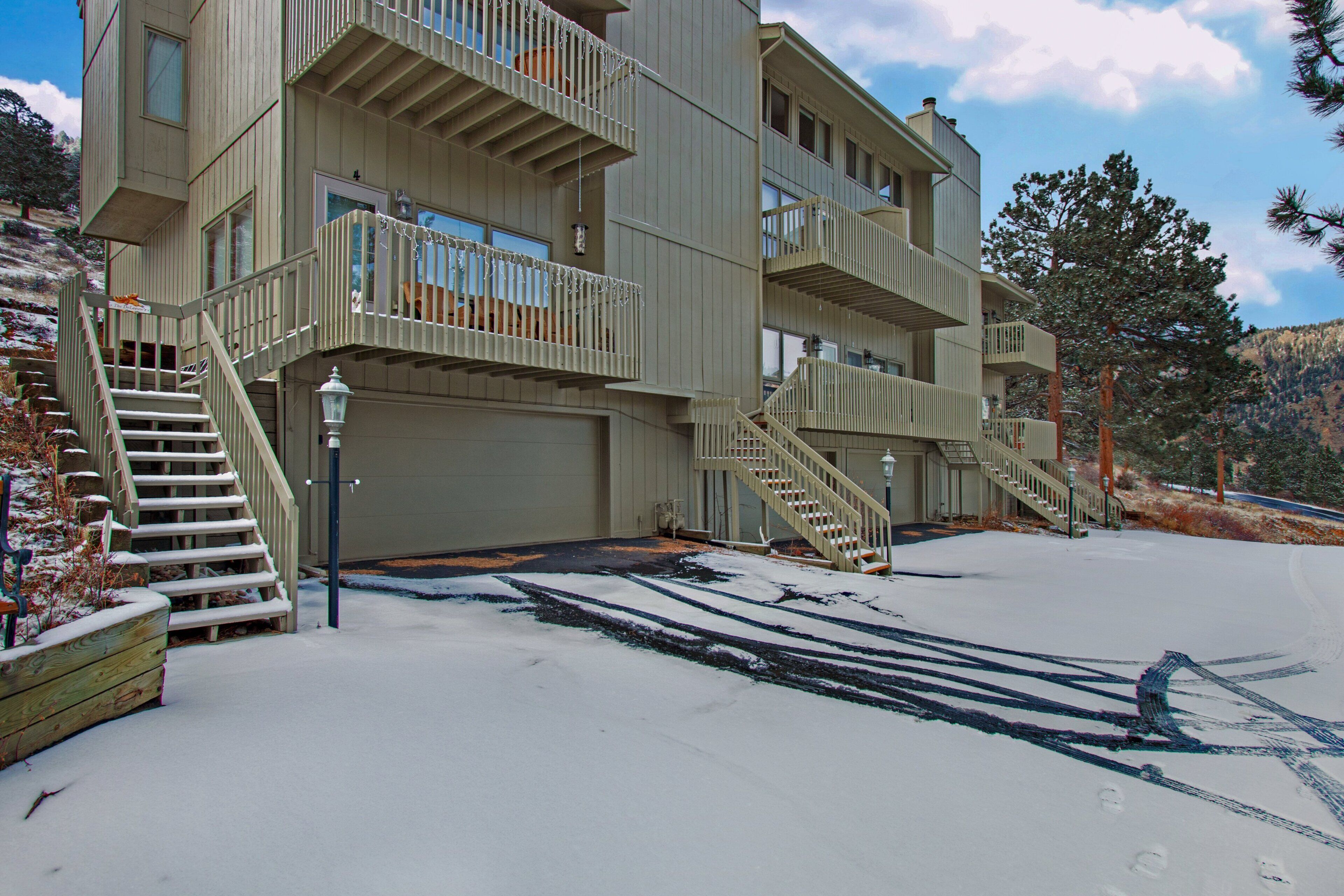 A multi-story building with balconies, a garage, and a snow-covered ground.