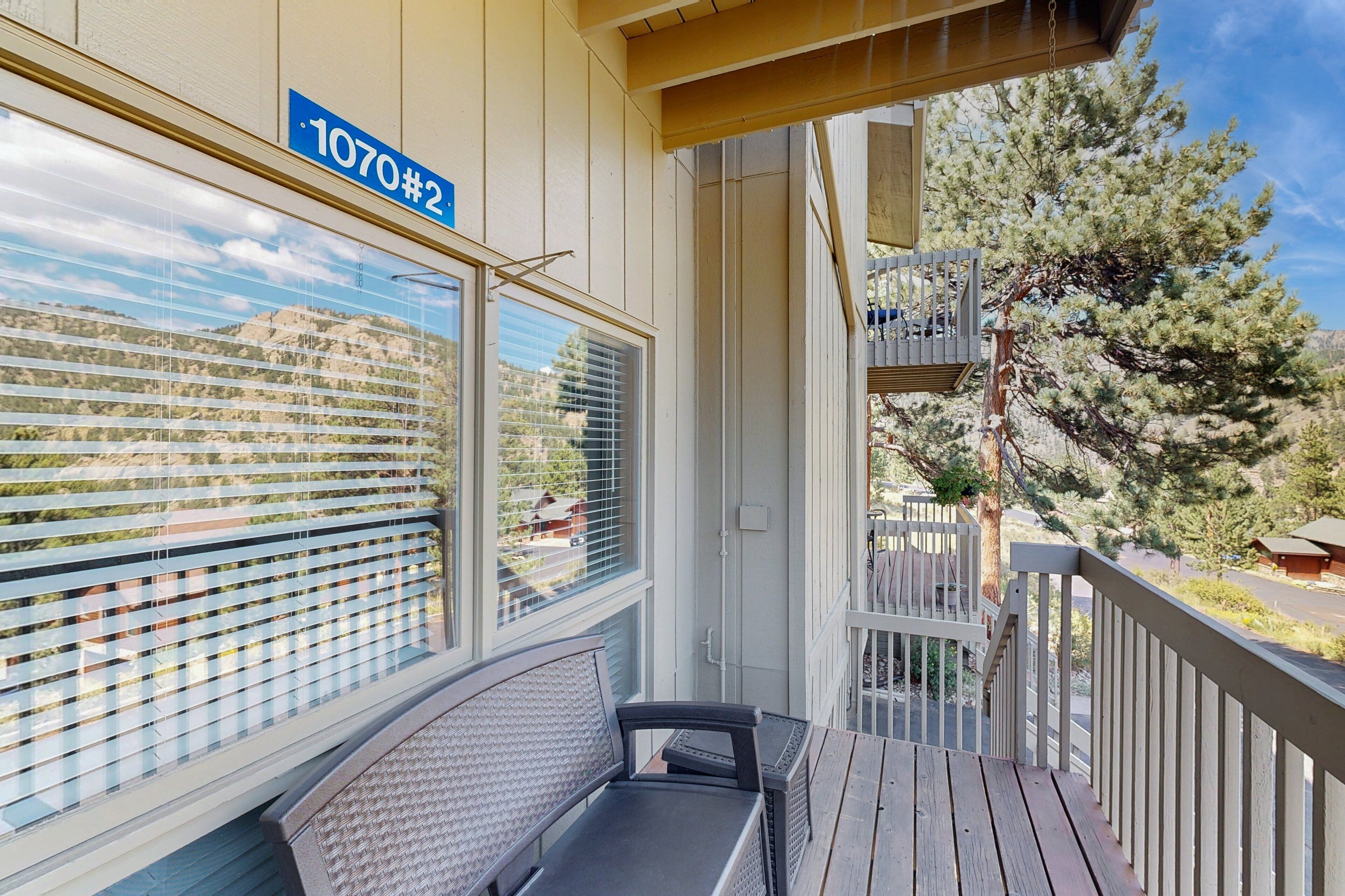 A balcony with a view of a mountain, a wooden bench, and a railing.
