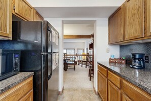 A kitchen with wooden cabinets, a black refrigerator, a microwave, and a coffee maker. - Comfortable Home With Breathtaking Mountain Views and High-speed Wifi (Estes Park)