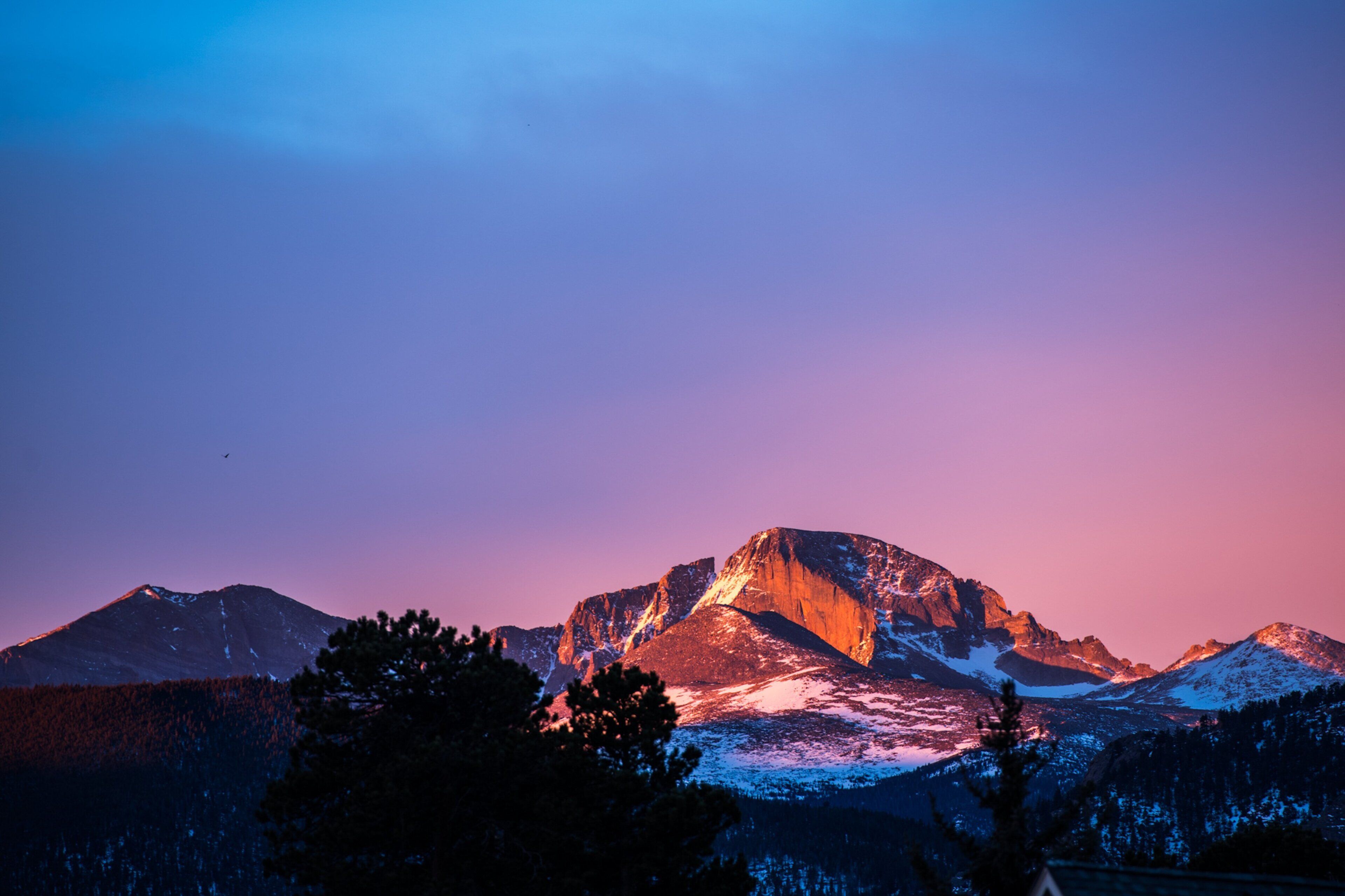 A mountain landscape with a prominent peak, surrounded by forested areas.
