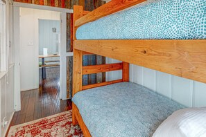 Ein Stockbett mit gemustertem Lattenrost, einem Holzkopfende und einem roten und weißen Teppich.