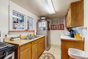 Eine kompakte Küche mit Holzausstattung, einer Spüle aus Edelstahl, einem Kühlschrank, einer Mikrowelle und einem Herd.