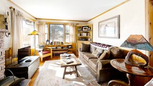 A cozy living room with a fireplace, a wooden coffee table, a sofa, and a bookshelf. - Delightful Getaway With Free Wifi, a Wood Fireplace, Washer/dryer, & Great Views (Estes Park)