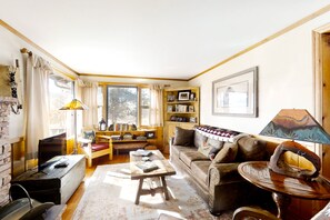 A cozy living room with a fireplace, a wooden coffee table, a sofa, and a bookshelf. - Delightful Getaway With Free Wifi, a Wood Fireplace, Washer/dryer, & Great Views (Estes Park)