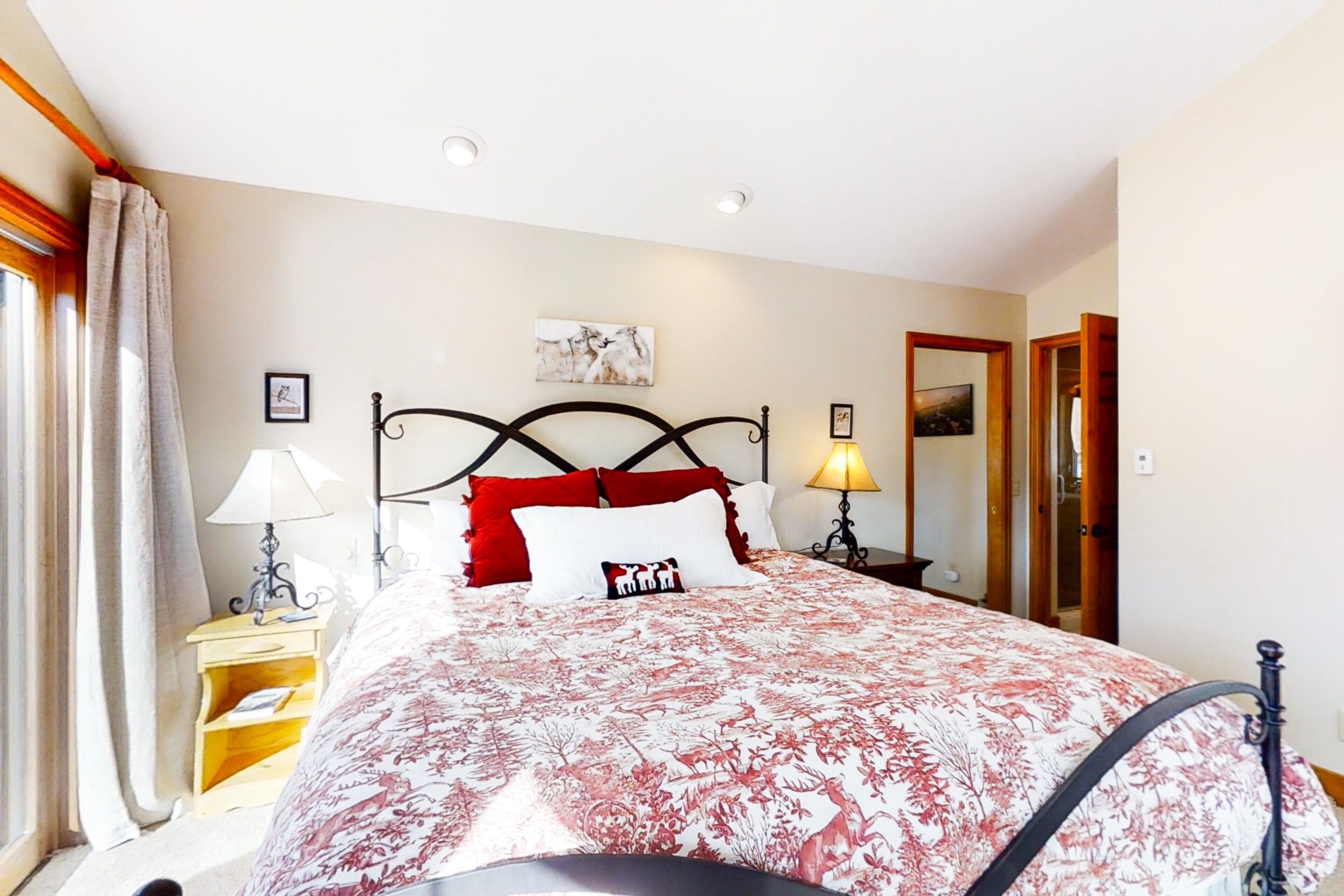 Une chambre à coucher avec un lit, des lampes de chevet, une table de chevet, un miroir et une porte.