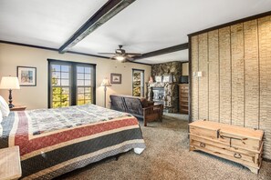 Quarto com cama, escrivaninha, cômoda, lareira e parede de pedra.