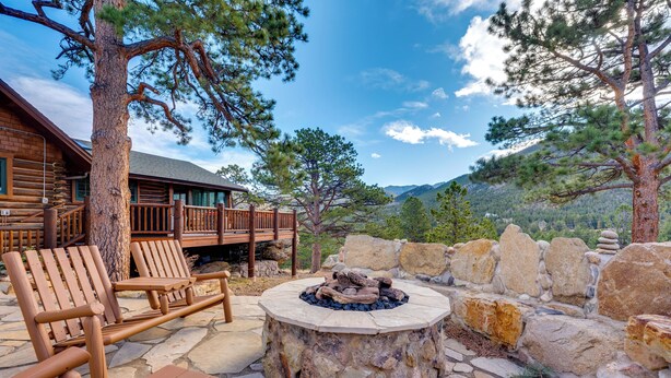 A wooden deck with lounge chairs and a stone fire pit. - Historic Cabin With Mountain Views, Private W/d, & Furnished Deck (Estes Park)