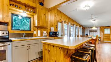 A kitchen with wooden cabinets, a large island with stools, a microwave, and a coffee maker.