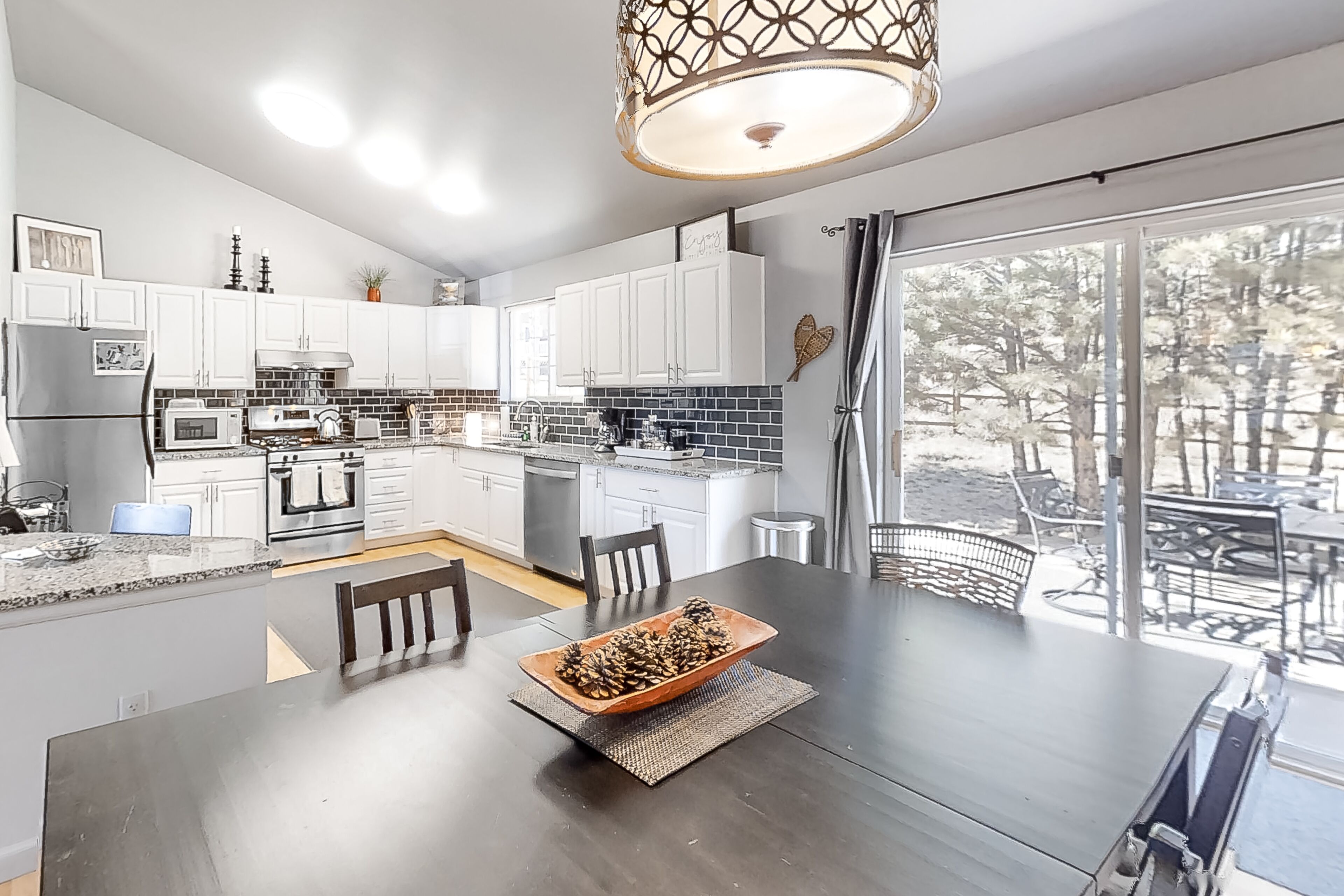Une cuisine moderne avec des meubles blancs, un grand îlot central et un coin repas comprenant une table et des chaises.
