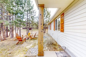 Eine Holzveranda mit Adirondack-Stühlen, einem Betonpodest und einem Metallgeländer.