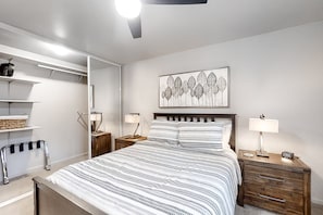 Ein Schlafzimmer mit Bett, Nachttischen, einem Kleiderschrank und einem Deckenventilator.